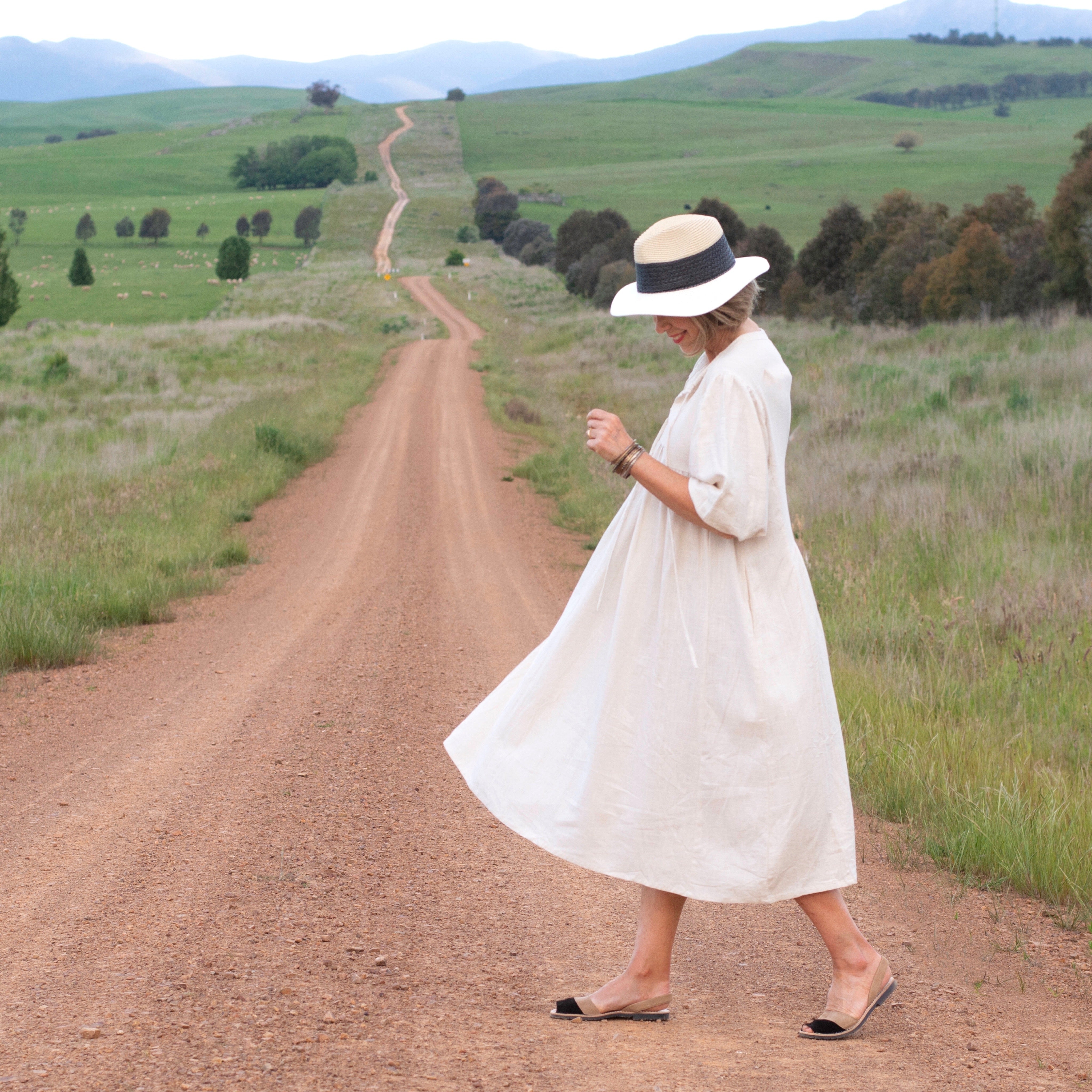 Lady in natural coloured linen dress in the country
